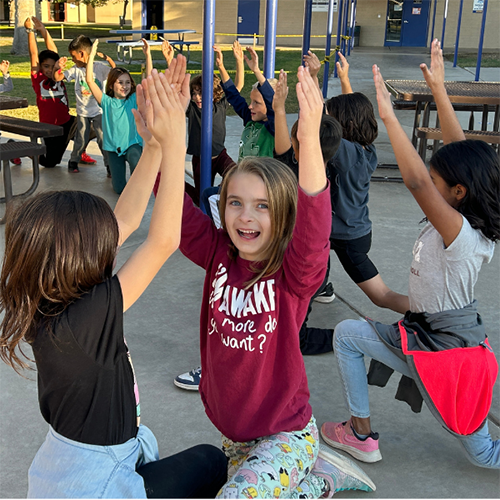 Happy girl raising arms up in the air during group activity