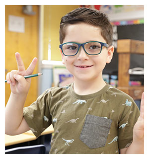 Little boy wearing glasses and olive green shirt showing the 